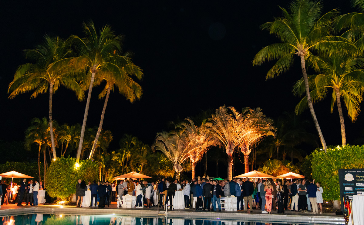 a group of people standing around a swimming pool at night